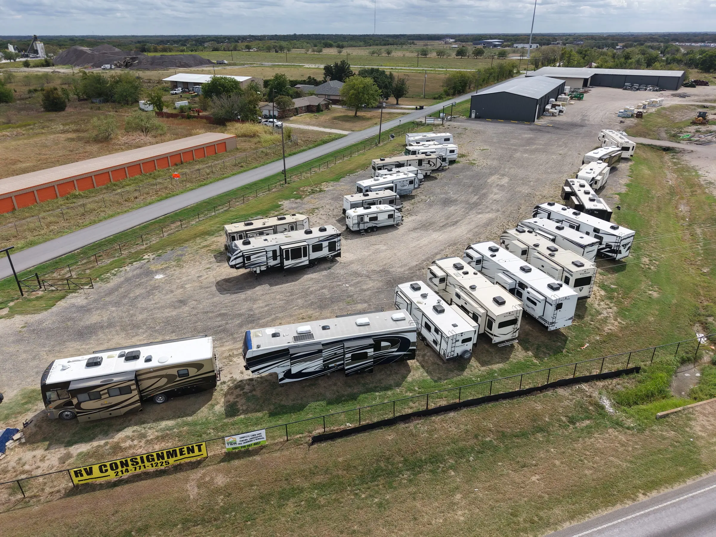 Aerial view of the fenced BK Consignments RV lot on the I-30 frontage road in Greenville, Texas, with fifth wheels and motorhomes parked in curving rows