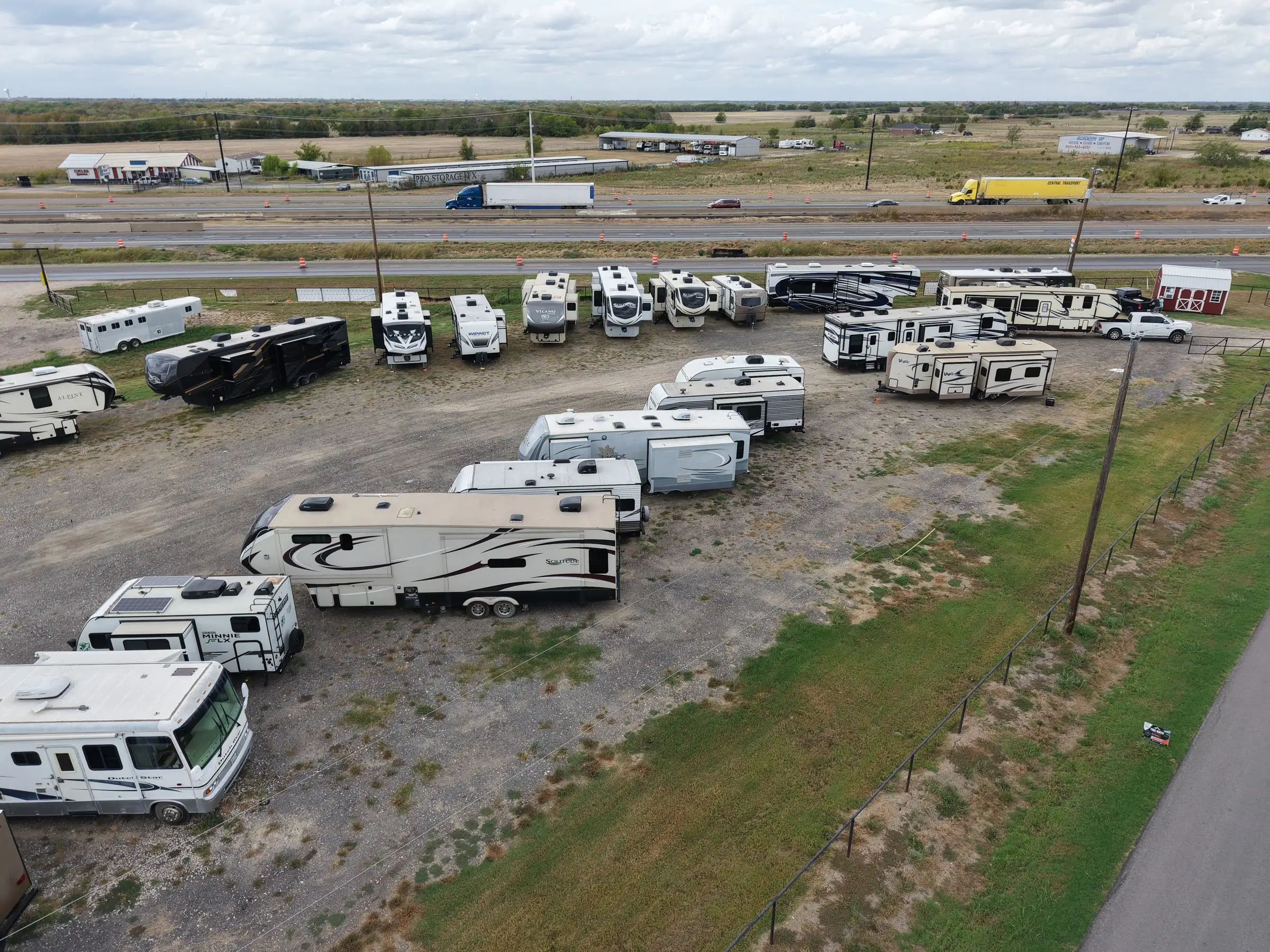 RVs for sale at BK Consignments beside Interstate 30 traffic in Hunt County, Texas, drone view