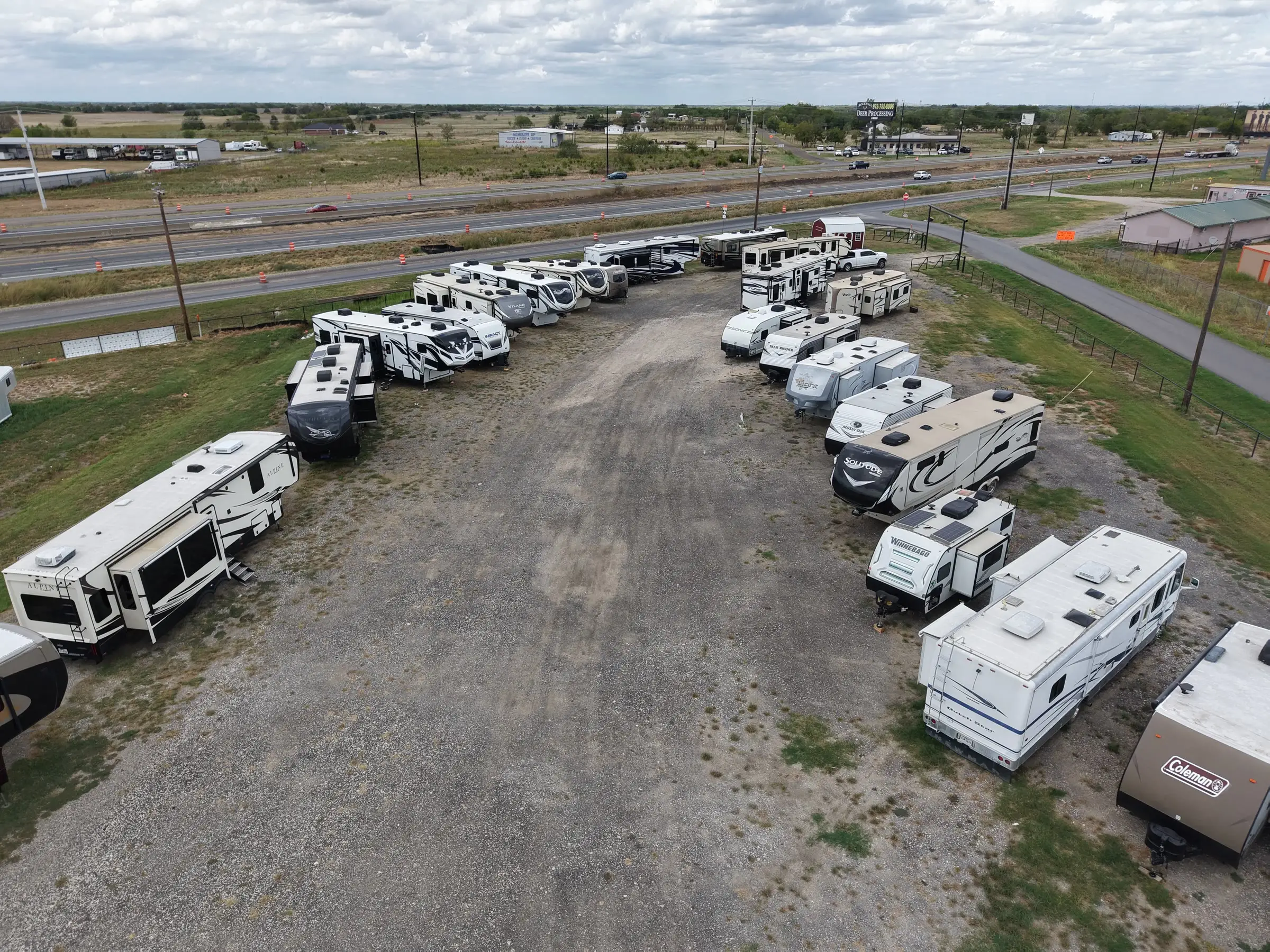 Aerial view of the center aisle at BK Consignments with travel trailers and fifth wheels on both sides and I-30 in the background